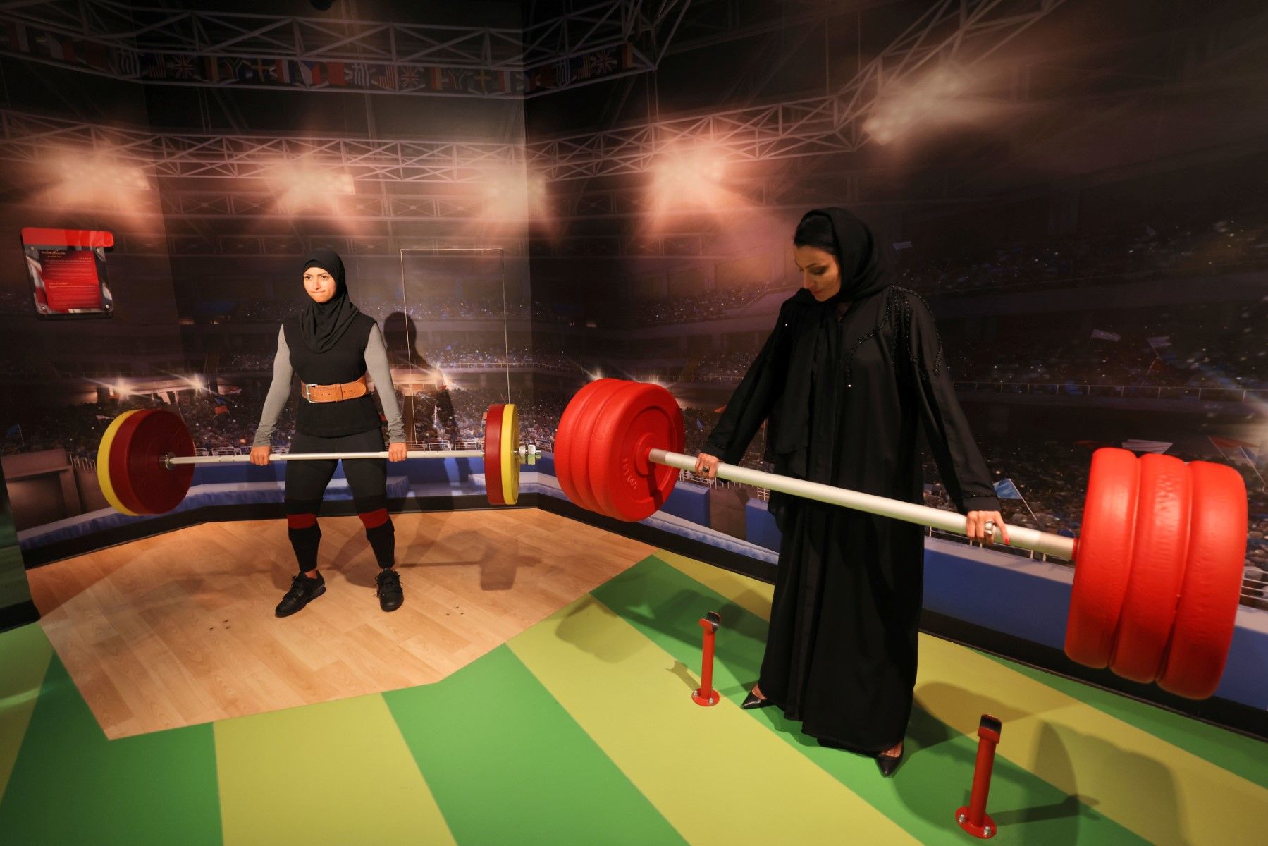 A visitor poses with a waxwork of weightlifter Amna Al Haddad at Madame Tussauds wax museum in Dubai/ AFP